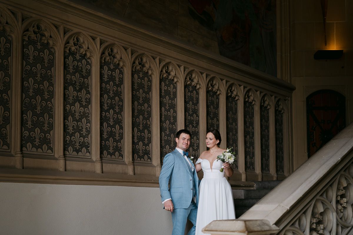 Newlywed couple sharing an intimate moment while posing on an ornate mansion staircase.