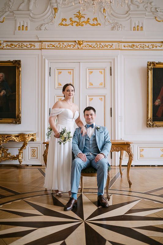 Centered editorial portrait beneath the chandelier, White Hall.