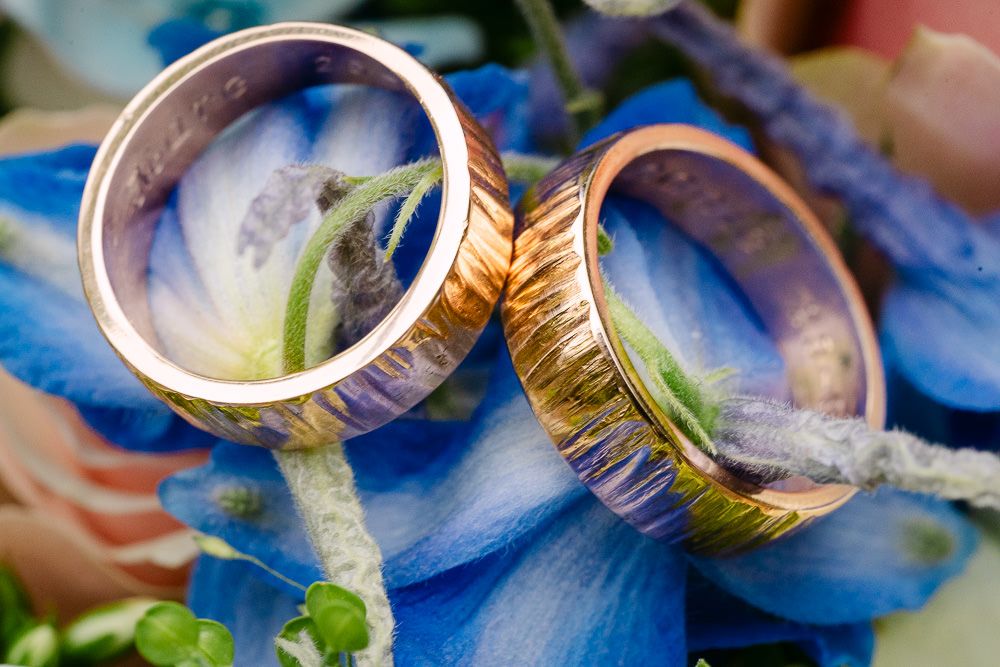 Artistic close-up of golden wedding rings on flowers at Kasteel Aerwinkel.