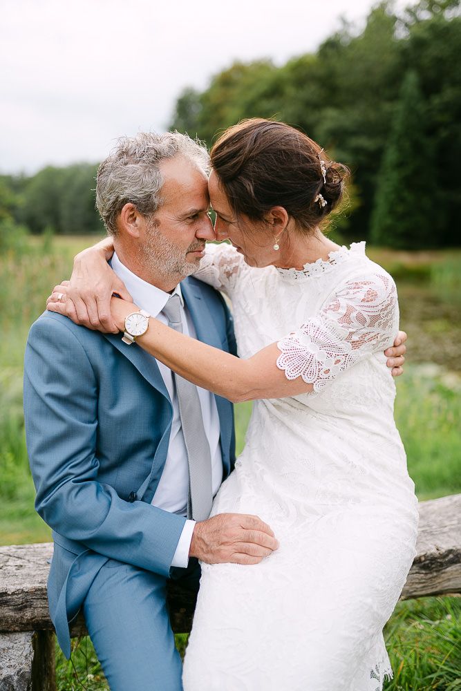 Bride and groom embracing on a stone bench in the gardens of Kasteel Aerwinkel.