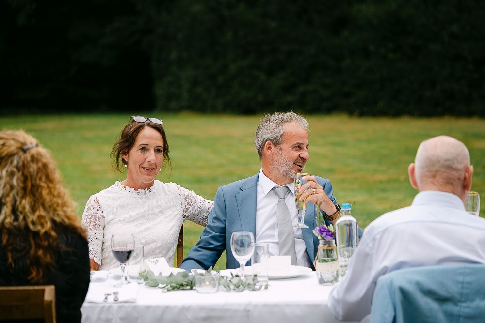 Bride and groom seated at the wedding dinner table with guests at Kasteel Aerwinkel.