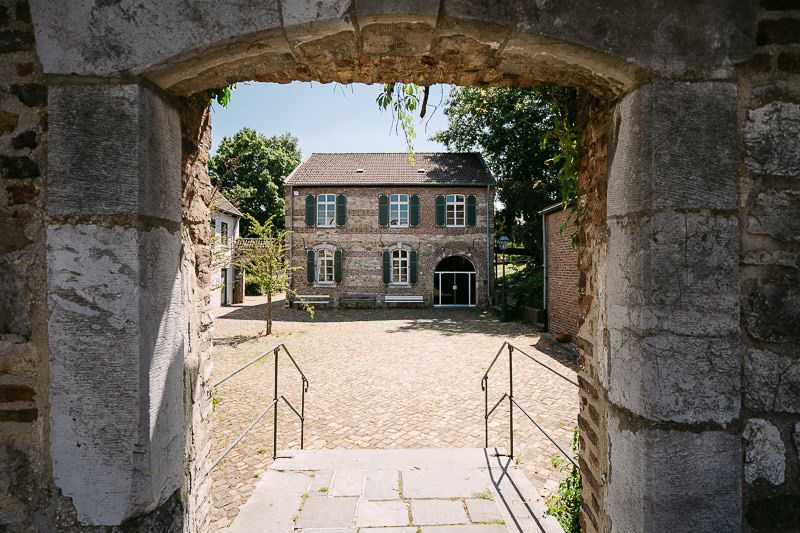 Die Welsche Mühle in Aachen Haaren, umrahmt vom Eingang in der Außenmauer.