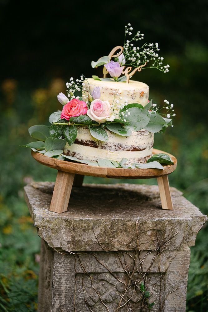 Wedding cake decorated with fresh flowers on a wooden stand at Kasteel Aerwinkel.