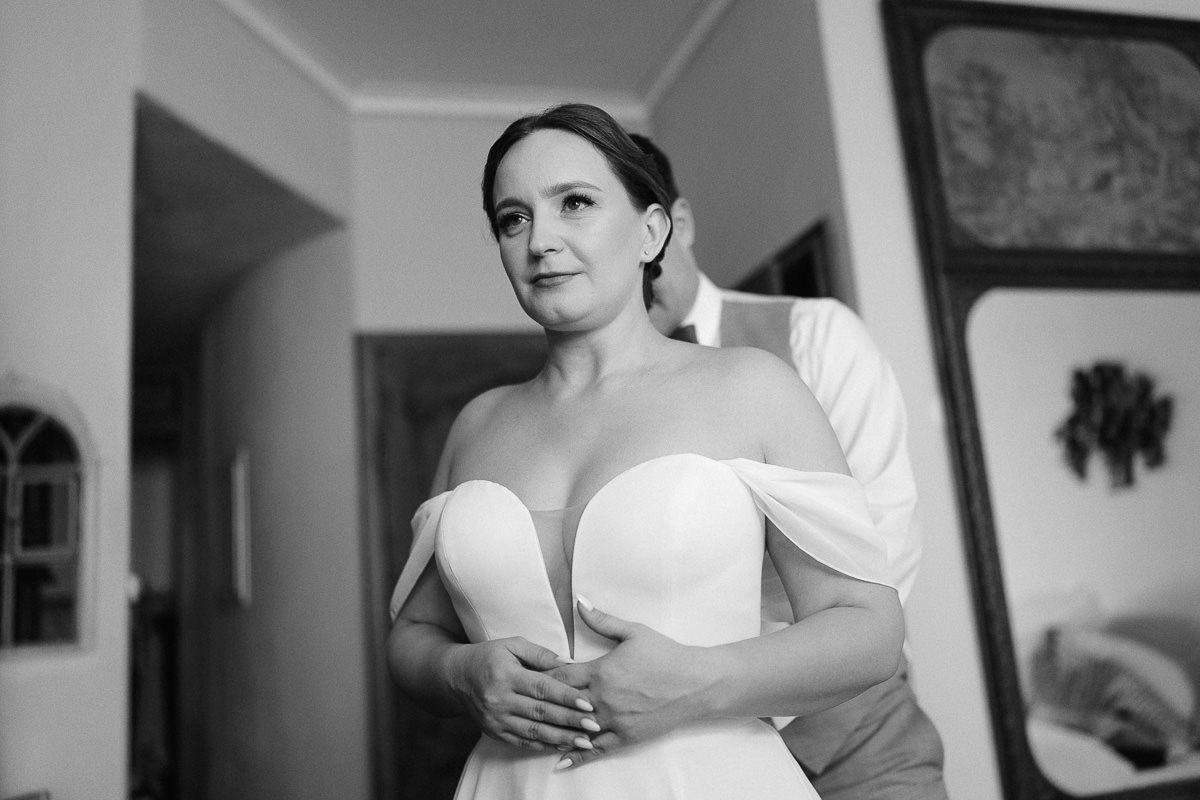 Bride steps into dress; minimal, elegant getting-ready moment.