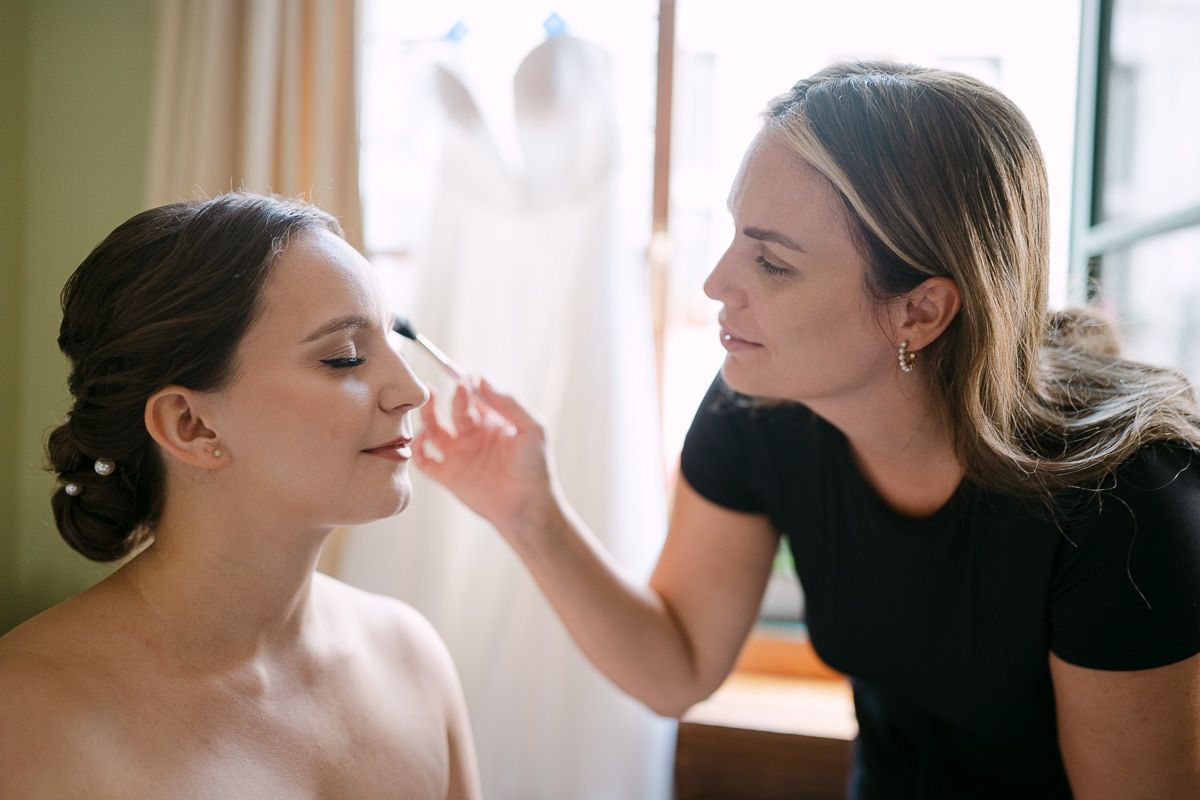 Bride getting makeup in soft window light in Aachen.