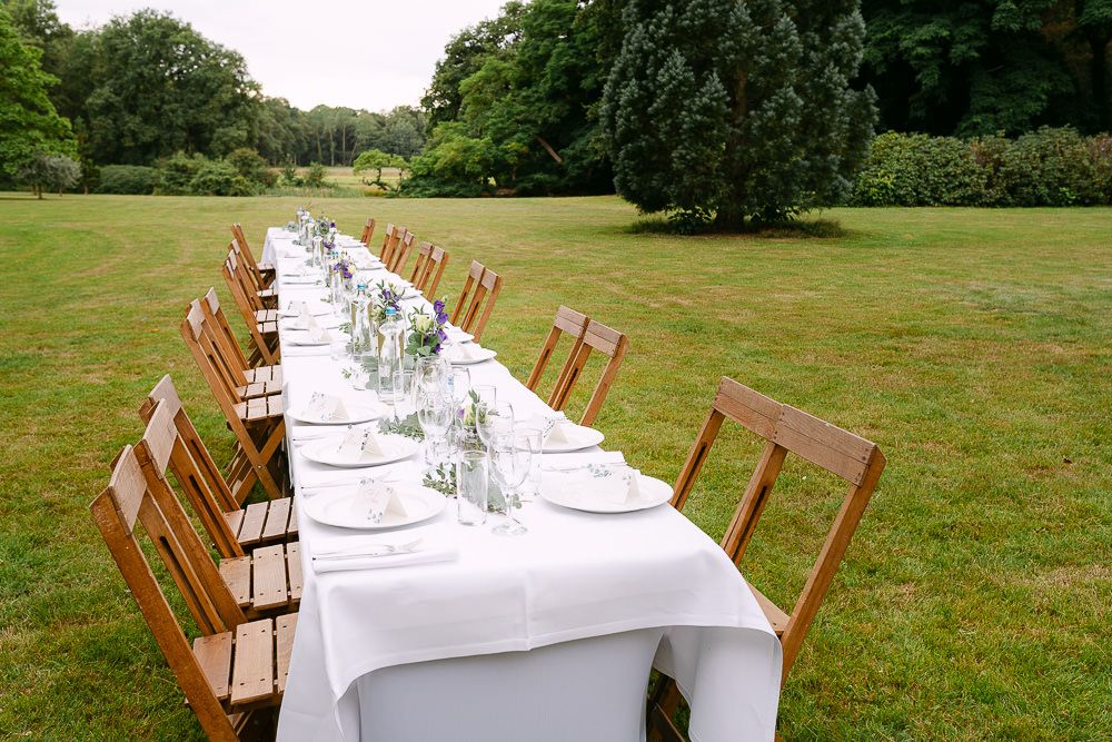 Long outdoor dining table decorated with greenery for a wedding reception at Kasteel Aerwinkel.