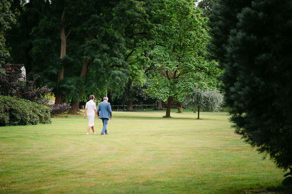 Bride and groom walking hand in hand across the garden of Kasteel Aerwinkel.