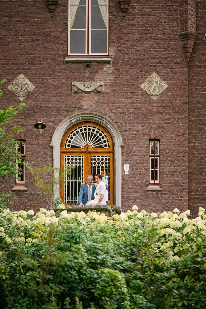 Bride and groom standing in front of the arched doorway of Kasteel Aerwinkel.