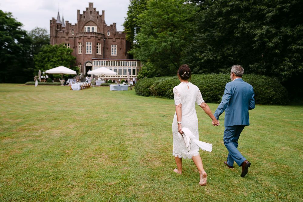 Bride and groom walking away together towards the castle at Kasteel Aerwinkel.