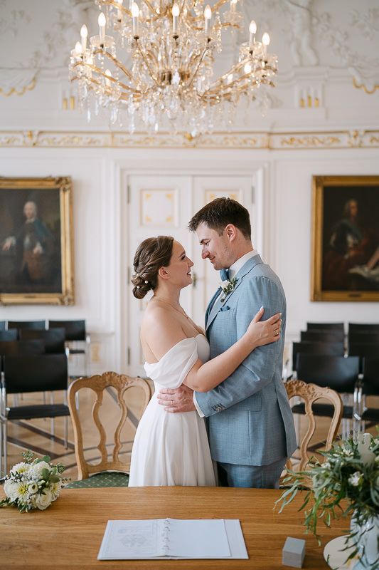 Newlyweds embrace under chandelier after the ceremony.