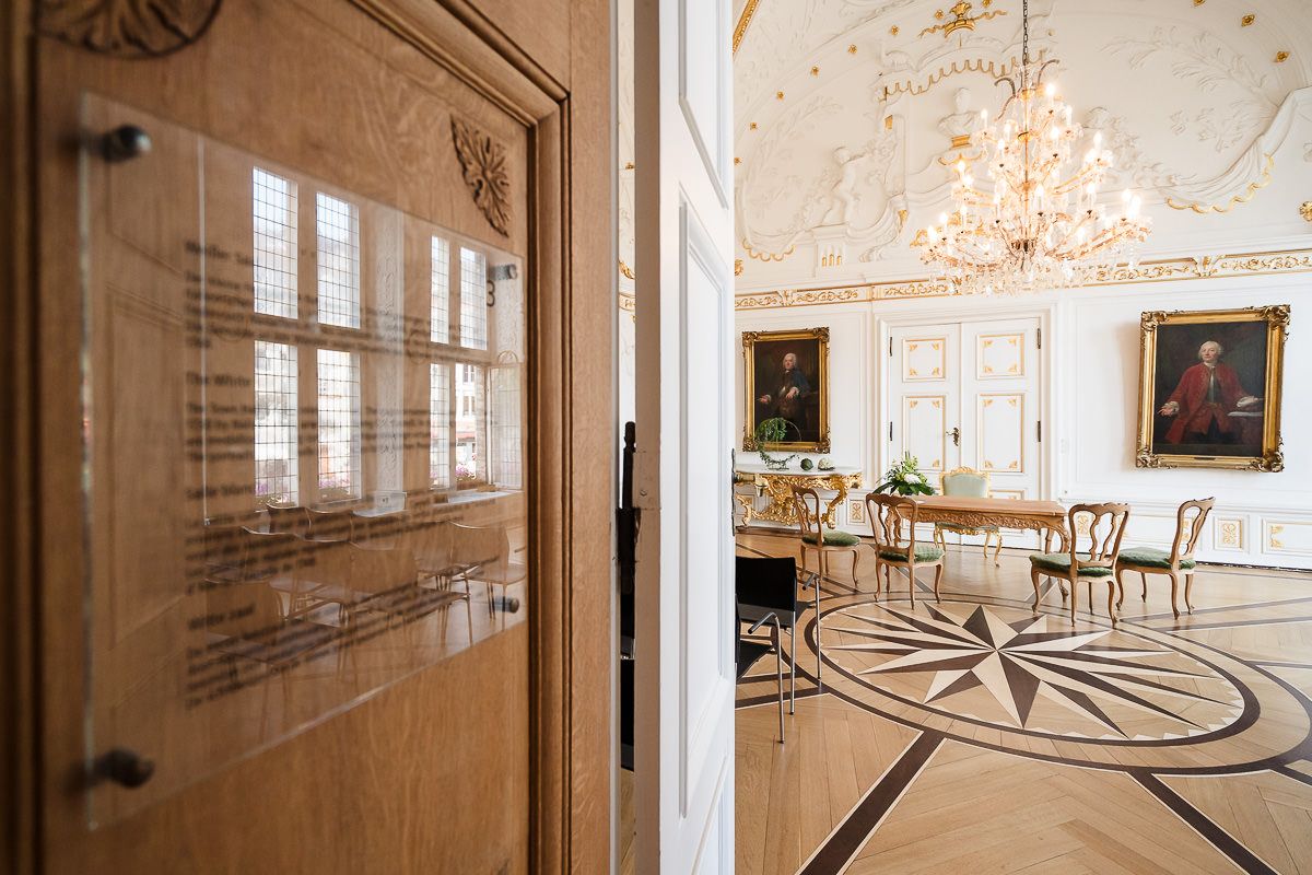 Elegantes Palastinterieur mit kunstvollen Kronleuchtern, Marmorböden und klassischen architektonischen Details in Weiß- und Goldtönen.