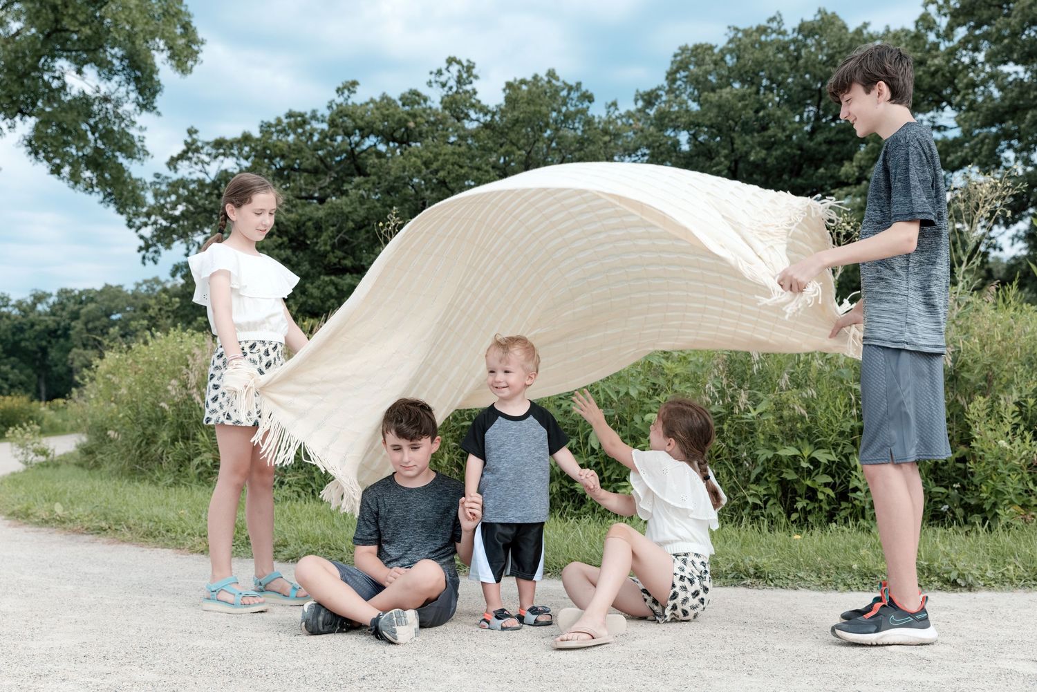 Boy and girl cousins having fun playing parachute at an Illinois forest preserve during a custom mini group portrait ses