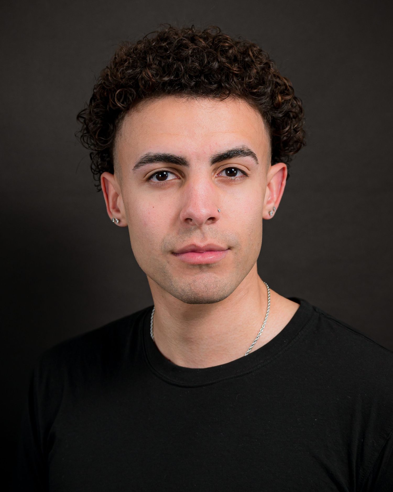 Studio headshot of person in black t-shirt against dark background.