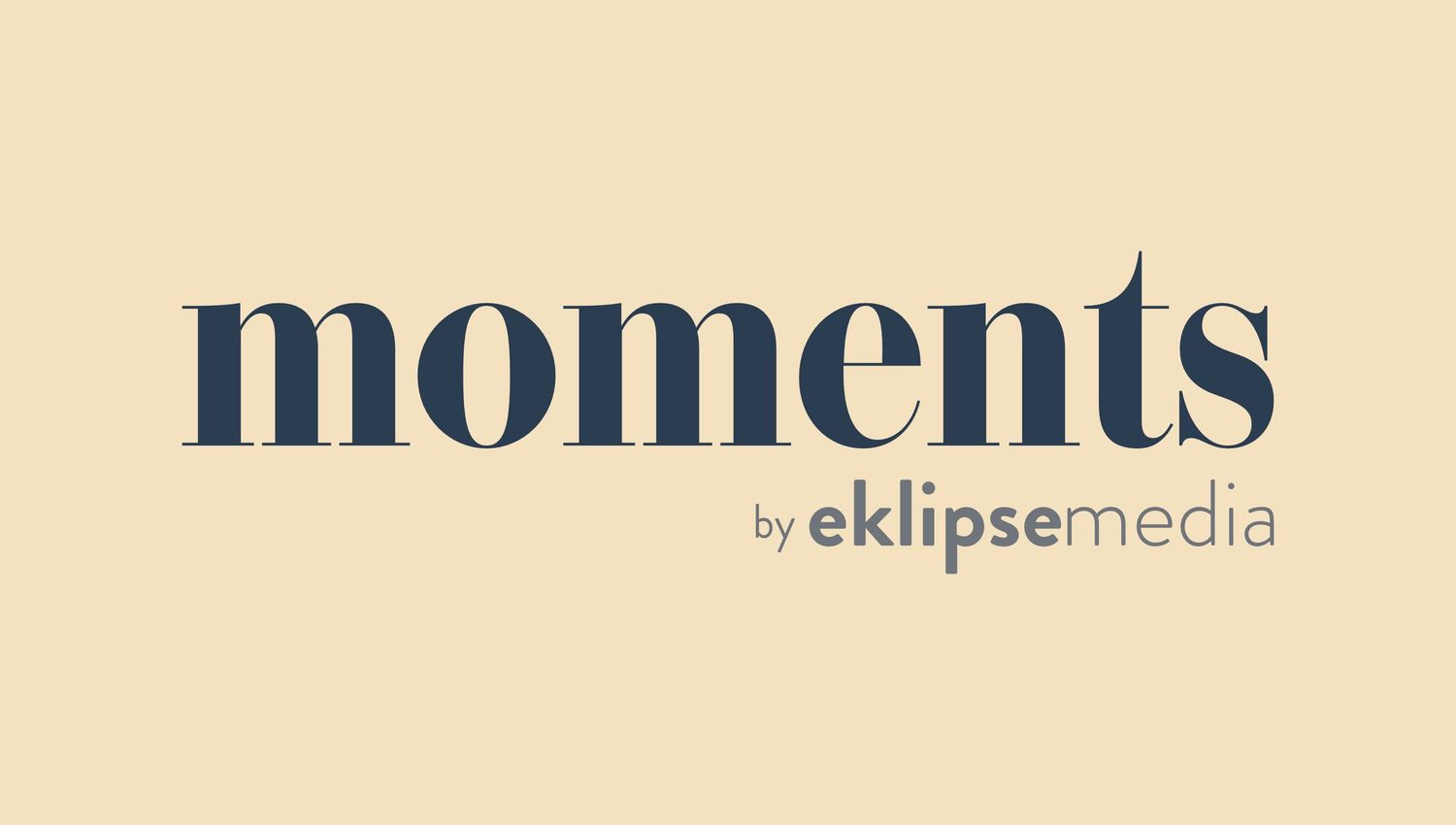 A stylized logo design showing the text 'moments by eklipse media' in dark blue against a beige background.