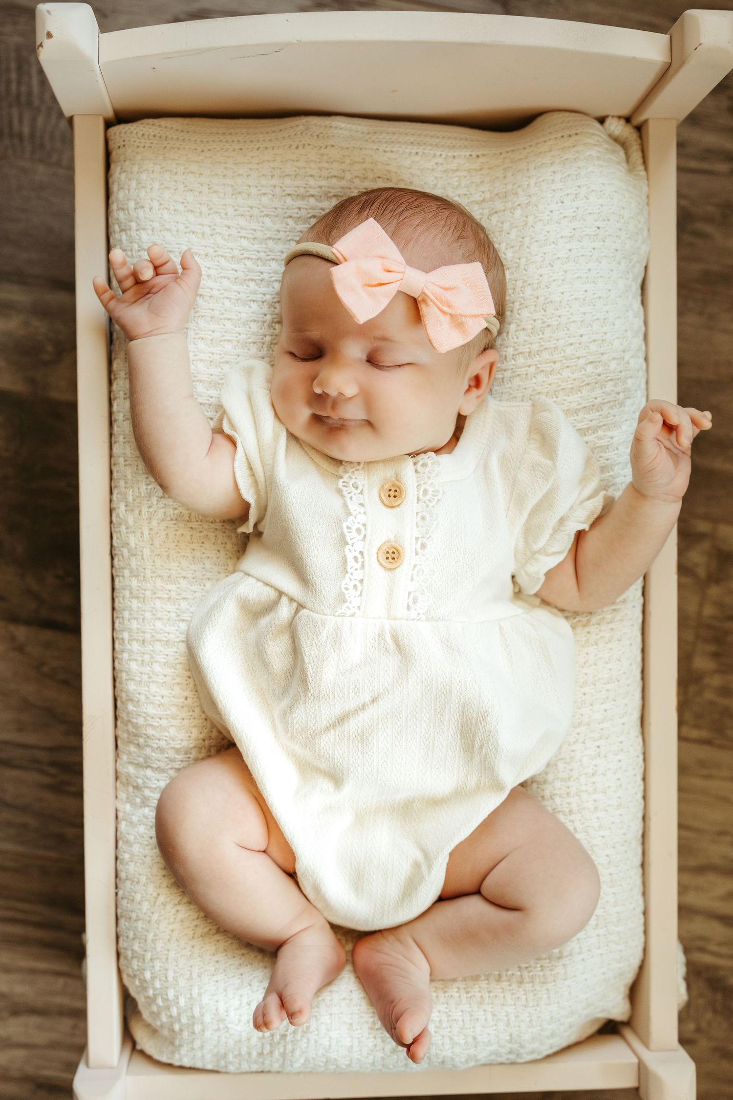 A baby wearing a white romper and peach bow rests on a textured white blanket in a series of lifestyle photos.