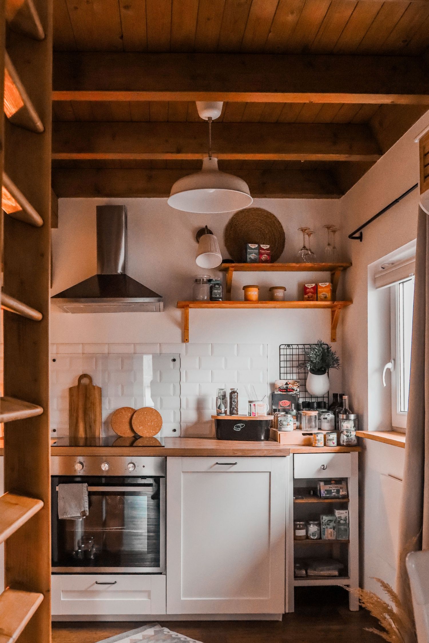 Rustic small kitchen with white cabinets, wooden countertops, open shelving, and wood beam ceiling.