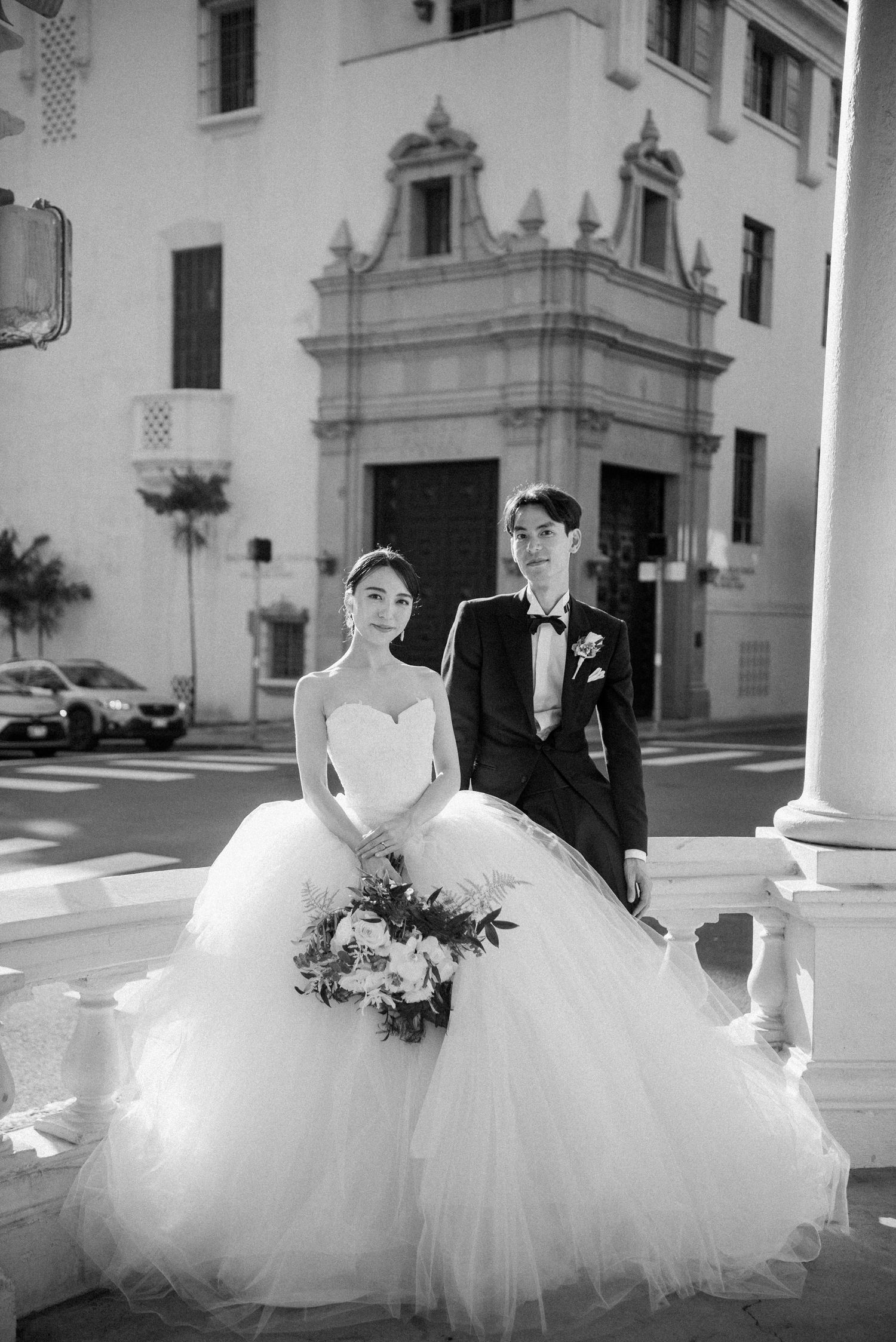 Black and white portrait of a newlywed couple outside their wedding venue