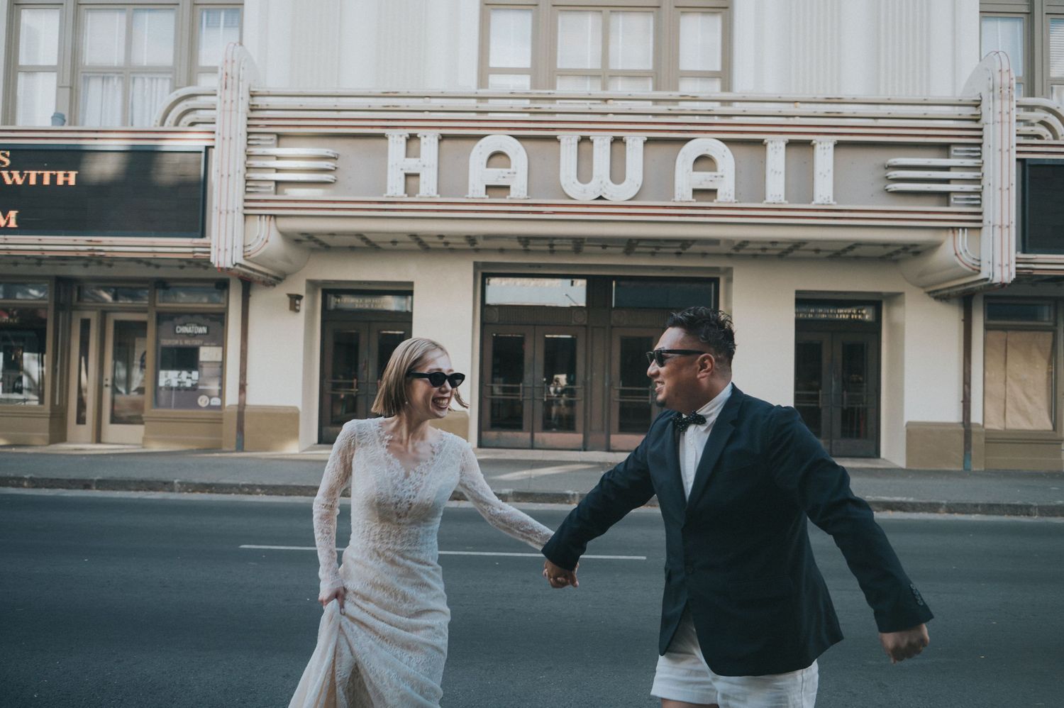 Newlywed couple walking hand in hand outside the Hawaii Theatre in downtown Honolulu