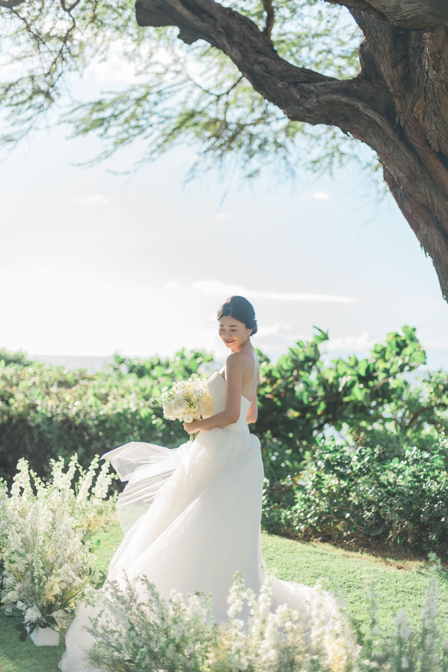 Bride walking beneath a tree during an outdoor wedding in Maui, Hawaii