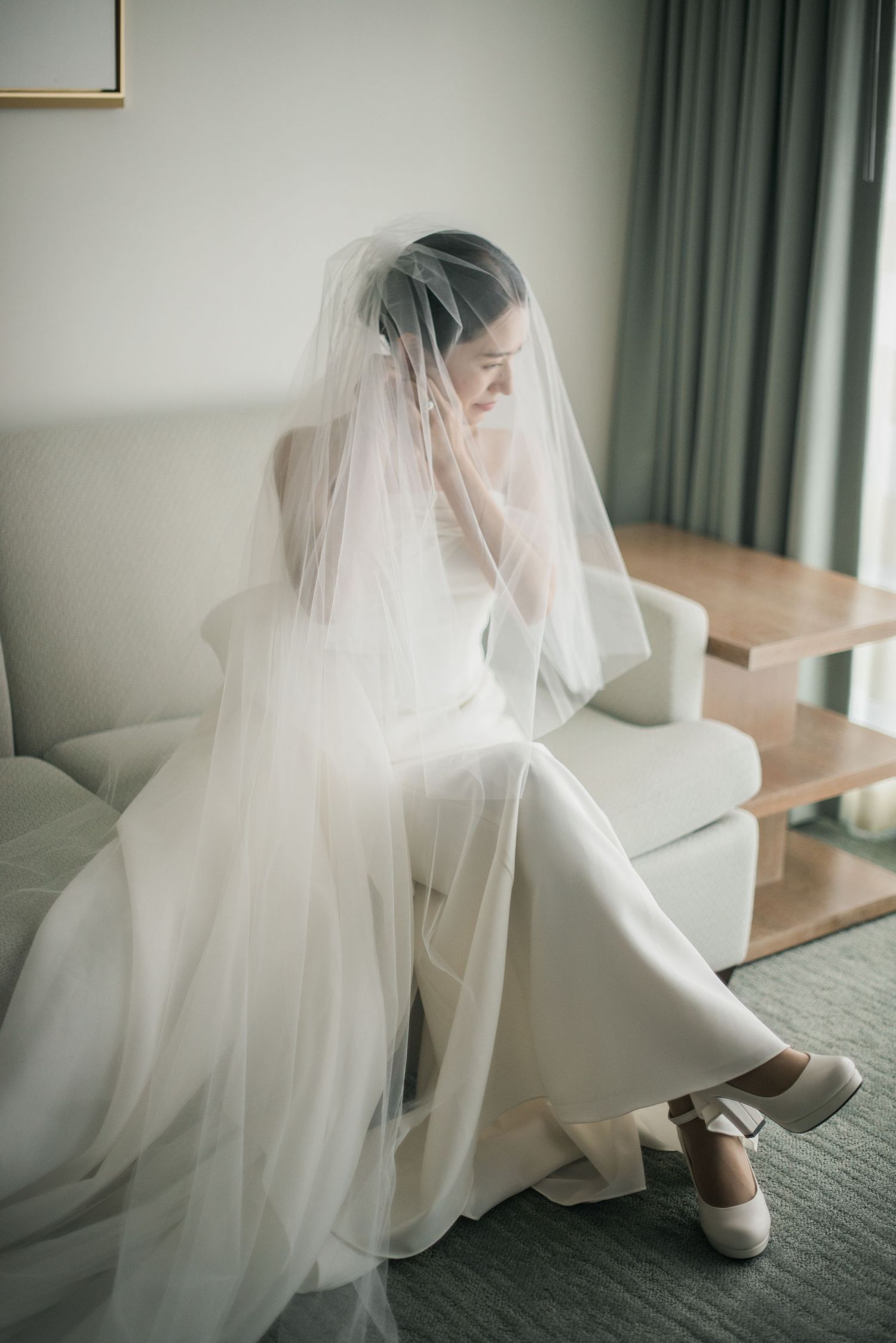 Bride in her wedding dress by the window during quiet getting-ready moments