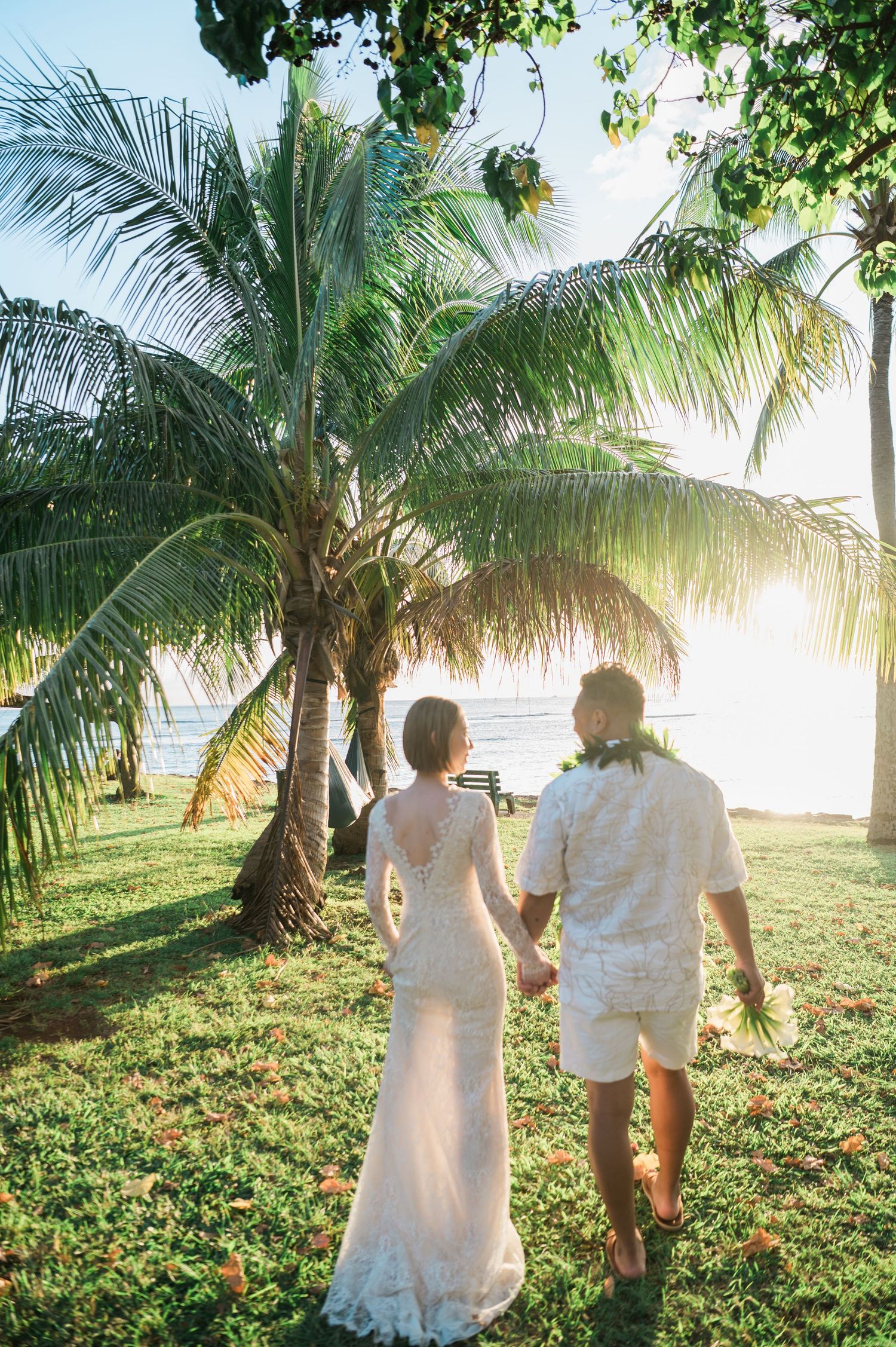 Newlywed couple walking beneath palm trees during a Hawaii elopement