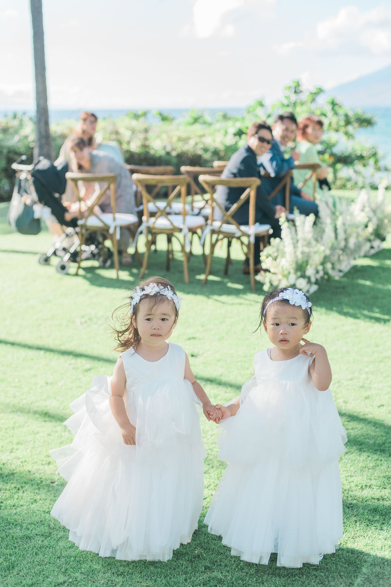 Two flower girls walking together during an outdoor wedding in Maui, Hawaii
