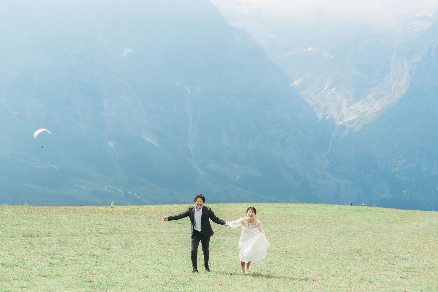 Newlywed couple running through a meadow in the Swiss Alps