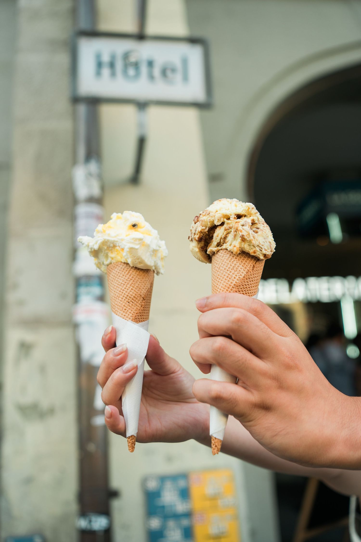 Two ice cream cones held up during a summer trip in Europe