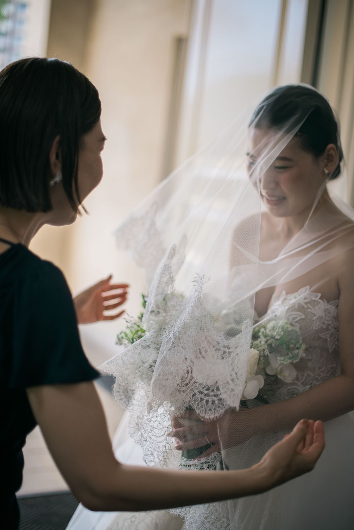 Bride in her veil sharing a quiet moment during wedding preparations