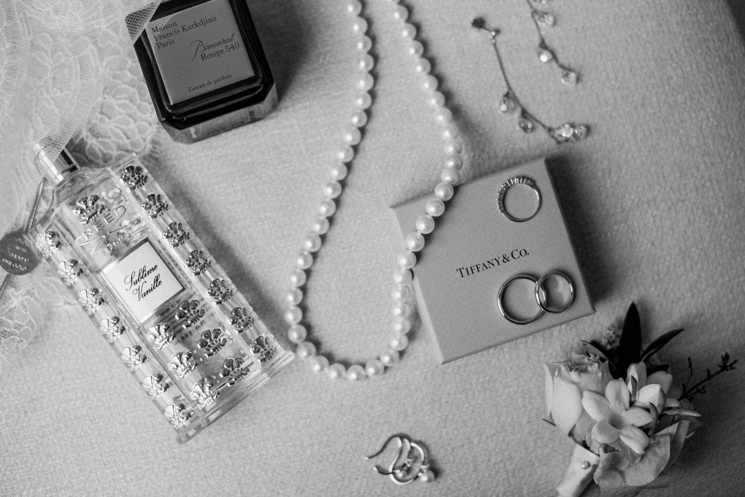 Black and white flat lay of wedding rings, jewelry, and bridal details