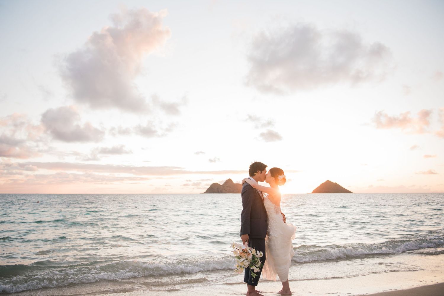 Newlywed couple embracing on the beach at sunset in Hawaii