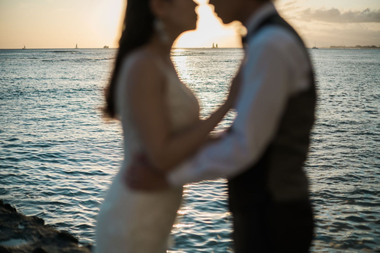 Newlywed couple embracing by the ocean at sunset in Hawaii