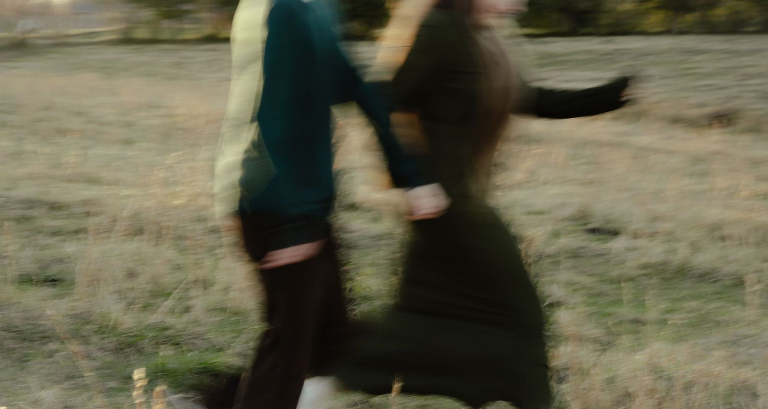 Two blurred figures in motion outdoors in a field, captured with motion blur effect.