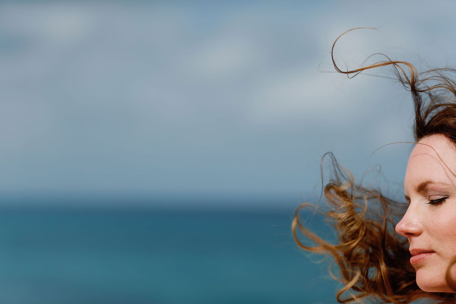 Artistic close-up of Li with windblown hair and the Caribbean Sea filling the background.