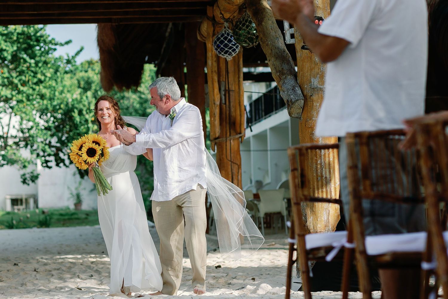 Li walks toward the Playa Norte ceremony with a loved one, carrying a sunflower bouquet.