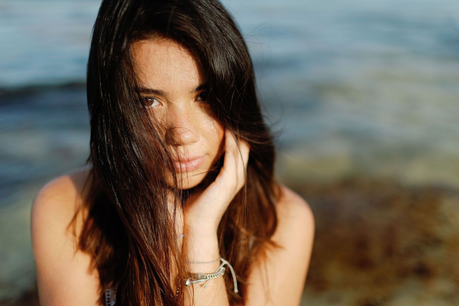 Beach senior portrait in Puerto Vallarta with natural sunlight, ocean backdrop, and candid expression during a coastal session.