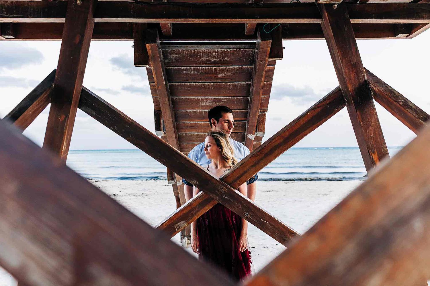 Artistic engagement portrait beneath a wooden beach structure in Punta Esmeralda Playa del Carmen.