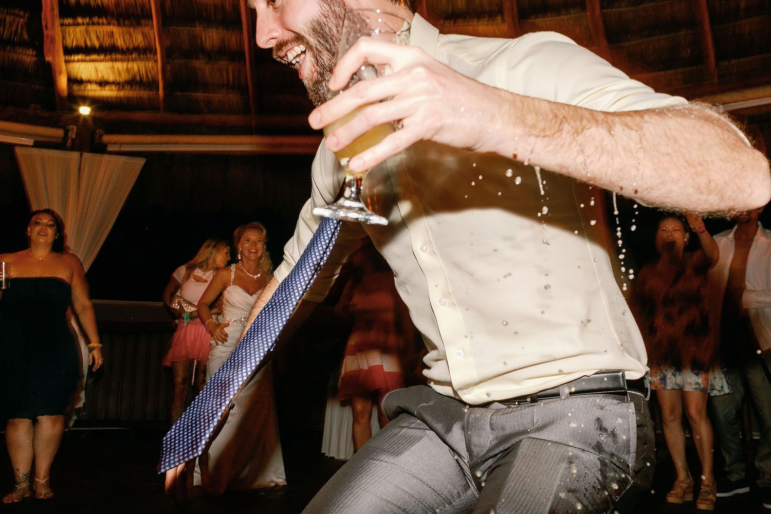 Guest dancing with a drink during the lively wedding reception