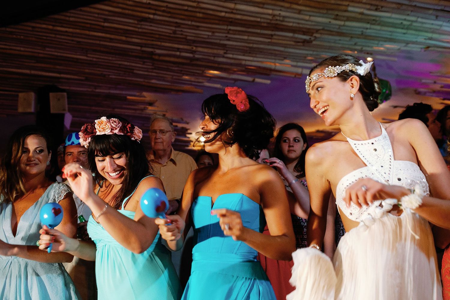 Juliana and her bridesmaids dance with colorful maracas at Fragata Beach Club.