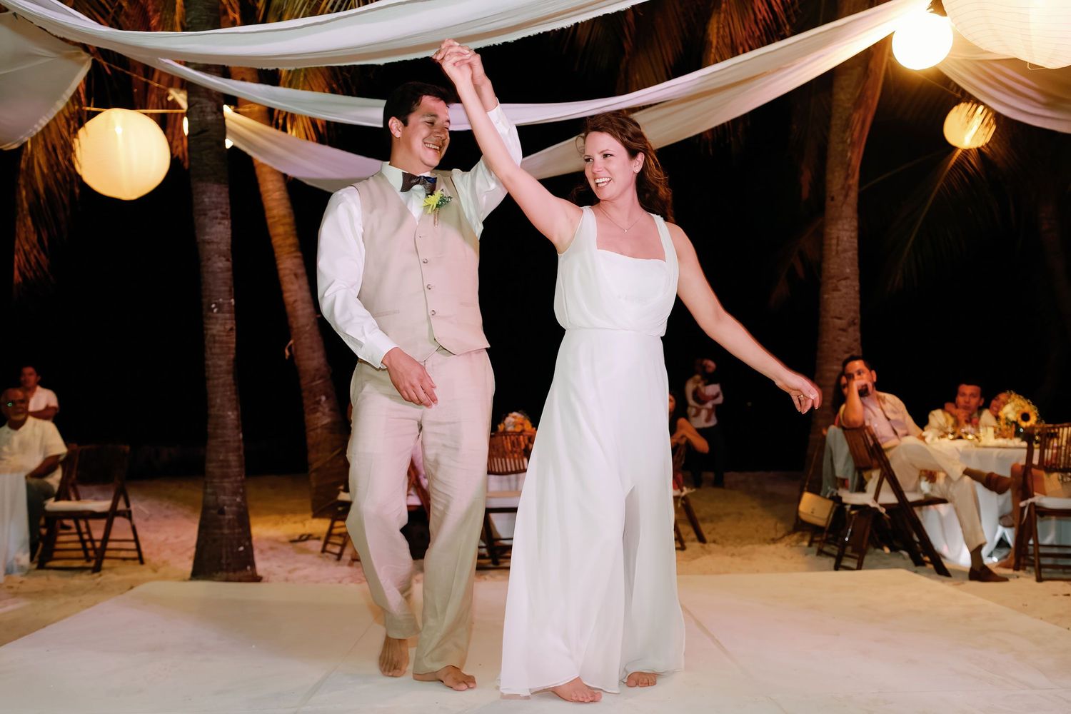 Li and Carlos dance barefoot under glowing lanterns at their Playa Norte wedding reception.