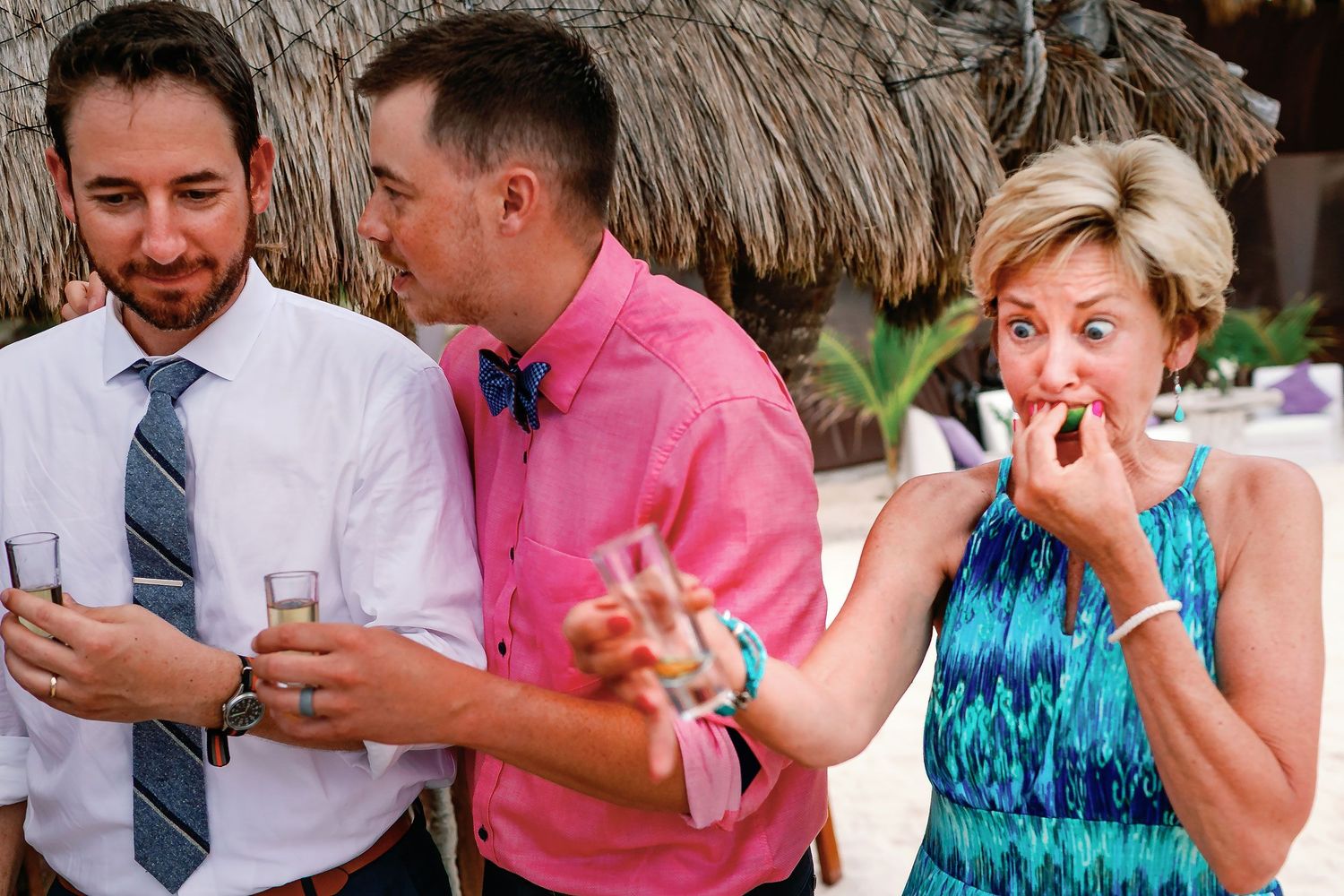 A guest bites a lime while holding a small glass as Matt and a friend stand beside her.