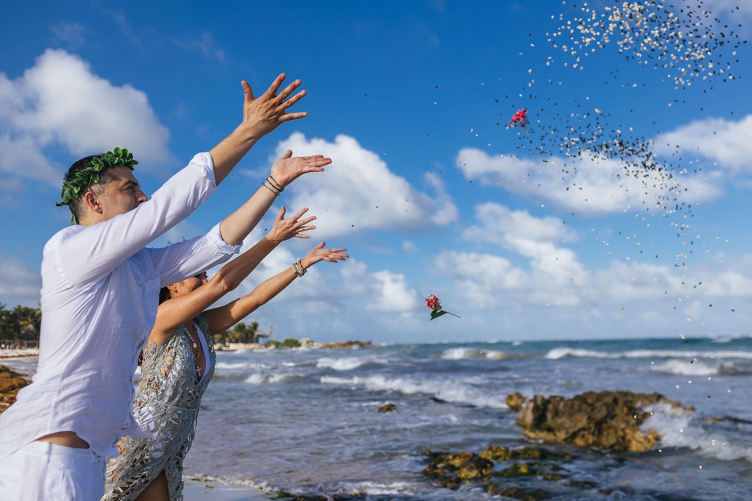 Sarah and Evish release flowers and small offerings into the sky beside the Caribbean