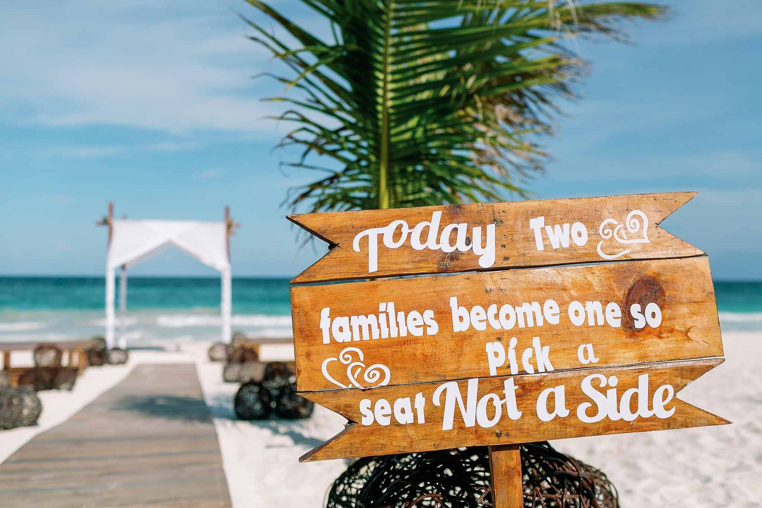 Rustic wedding welcome sign on the beach at Planet Hollywood Costa Mujeres with oceanfront ceremony setup in Cancun.