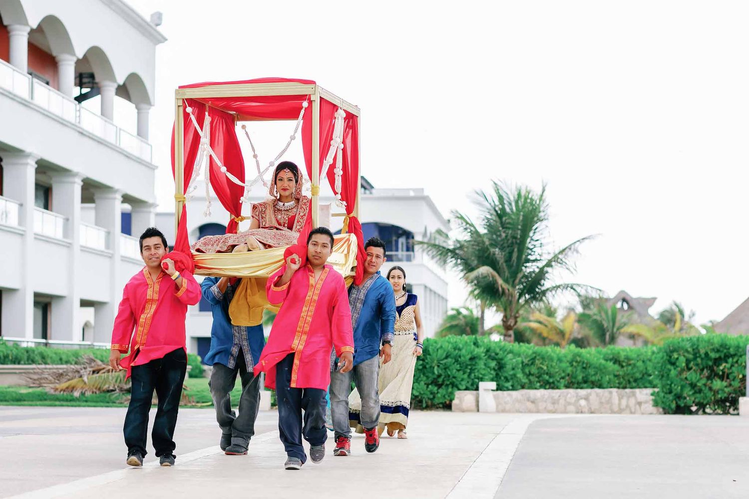 Indian bride making traditional bridal entrance at Hard Rock Riviera Maya carried in decorated doli during luxury Hindu destination wedding