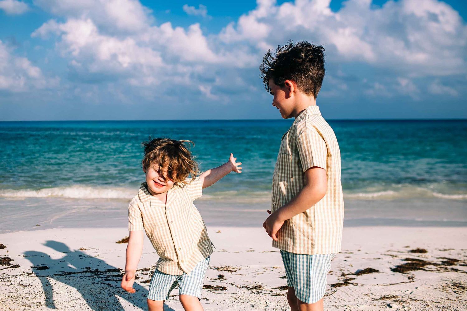 Two brothers playing on the beach during a family photography session at Fairmont Mayakoba in Playa del Carmen.