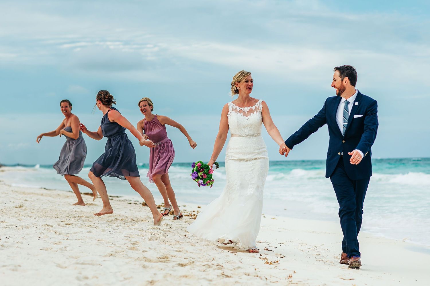 Ashley and Matt lead their laughing wedding party along the Caribbean beach in Tulum.