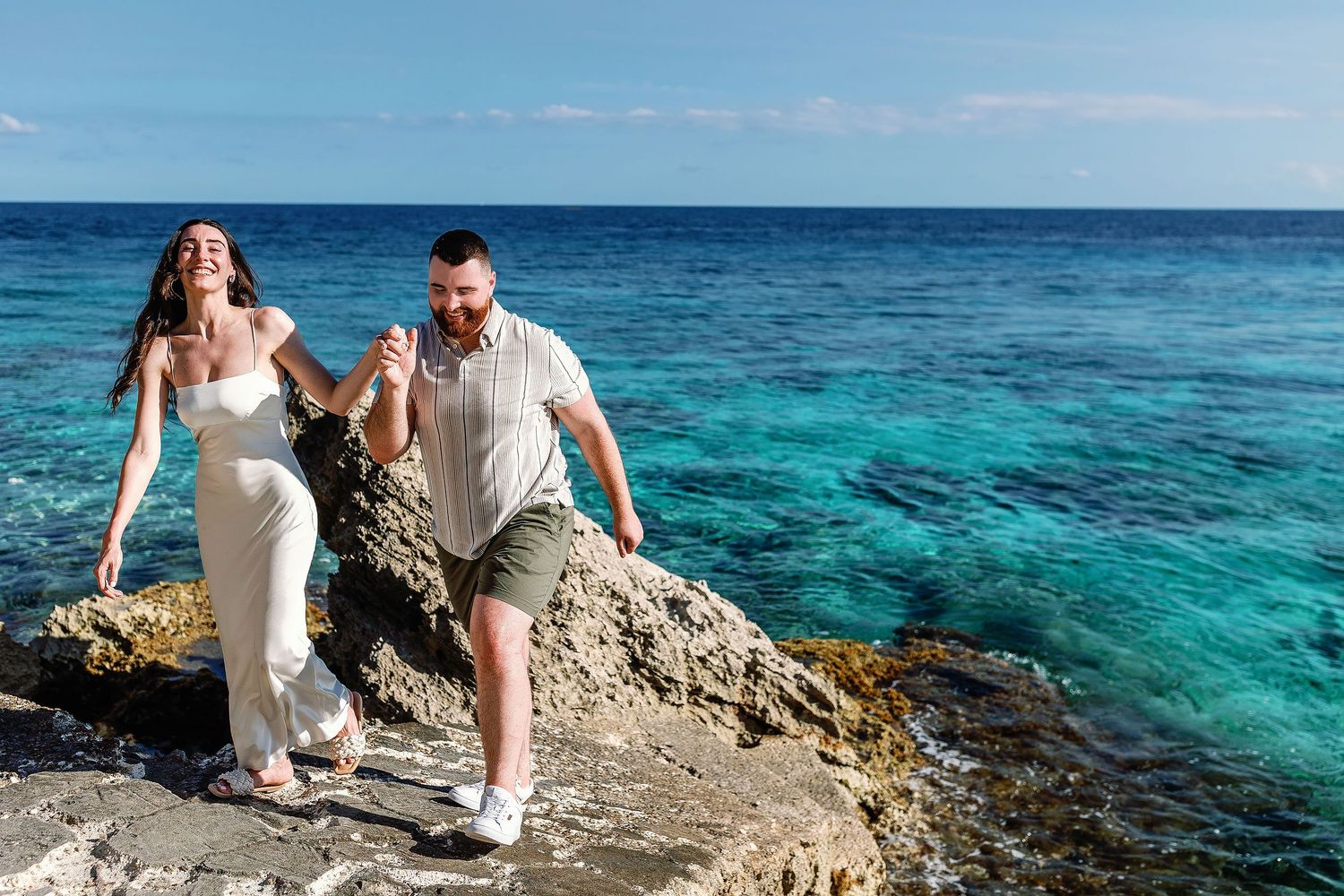 A laughing Alexia walks hand in hand with Sam beside Punta Sur’s turquoise water.
