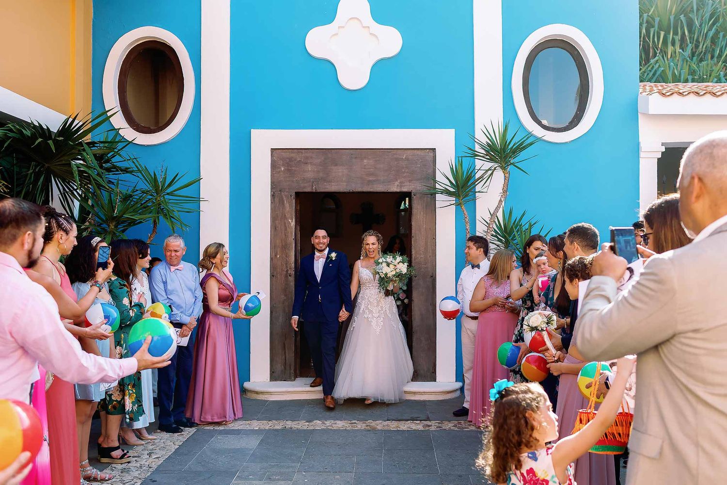 Bride and groom exit Dreams Tulum chapel with guests celebrating, colorful Catholic wedding ceremony in Tulum Mexico