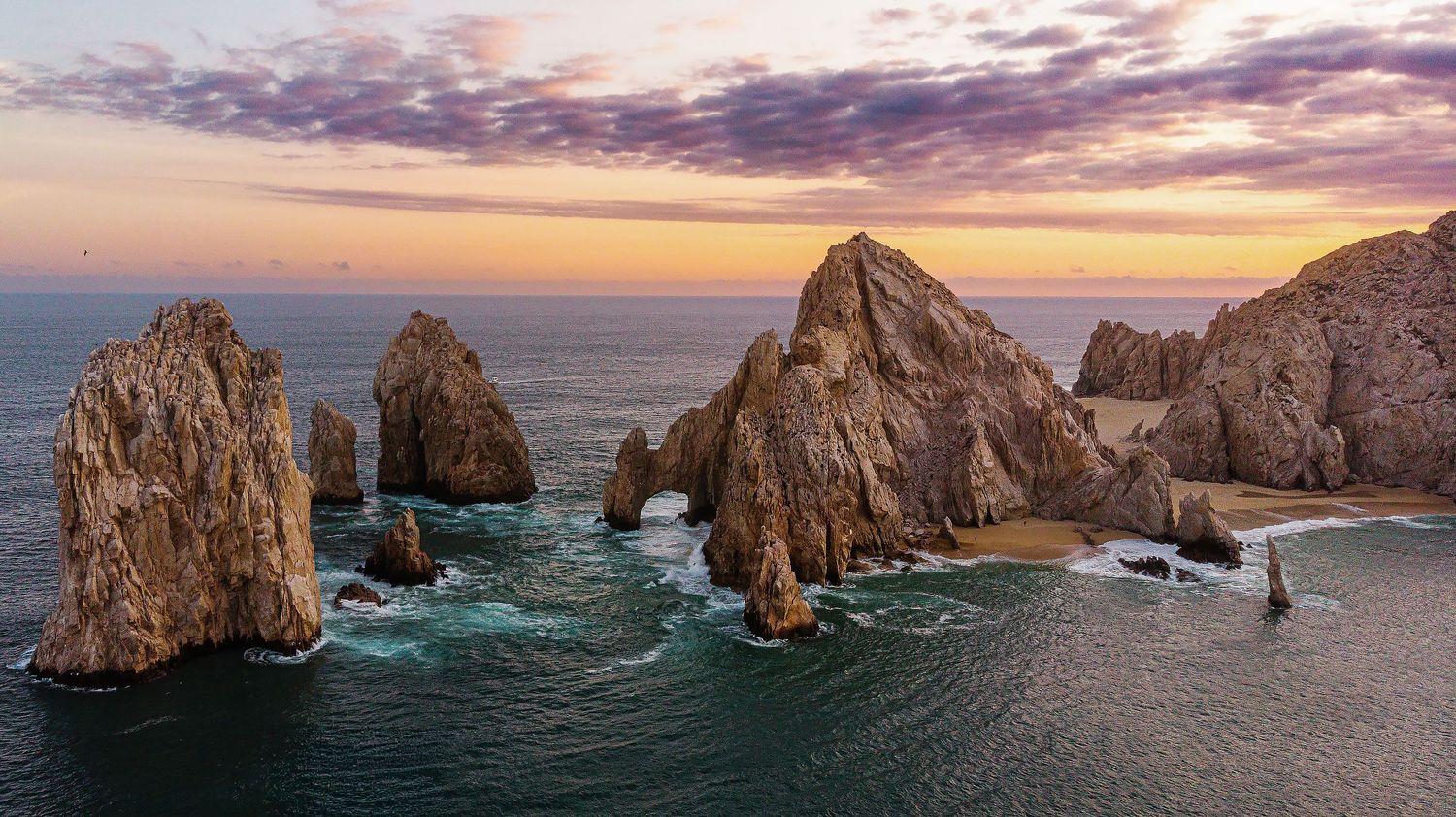 Aerial photograph of El Arco in Cabo San Lucas, Los Cabos, featuring the dramatic coastline and Sea of Cortez at sunrise.