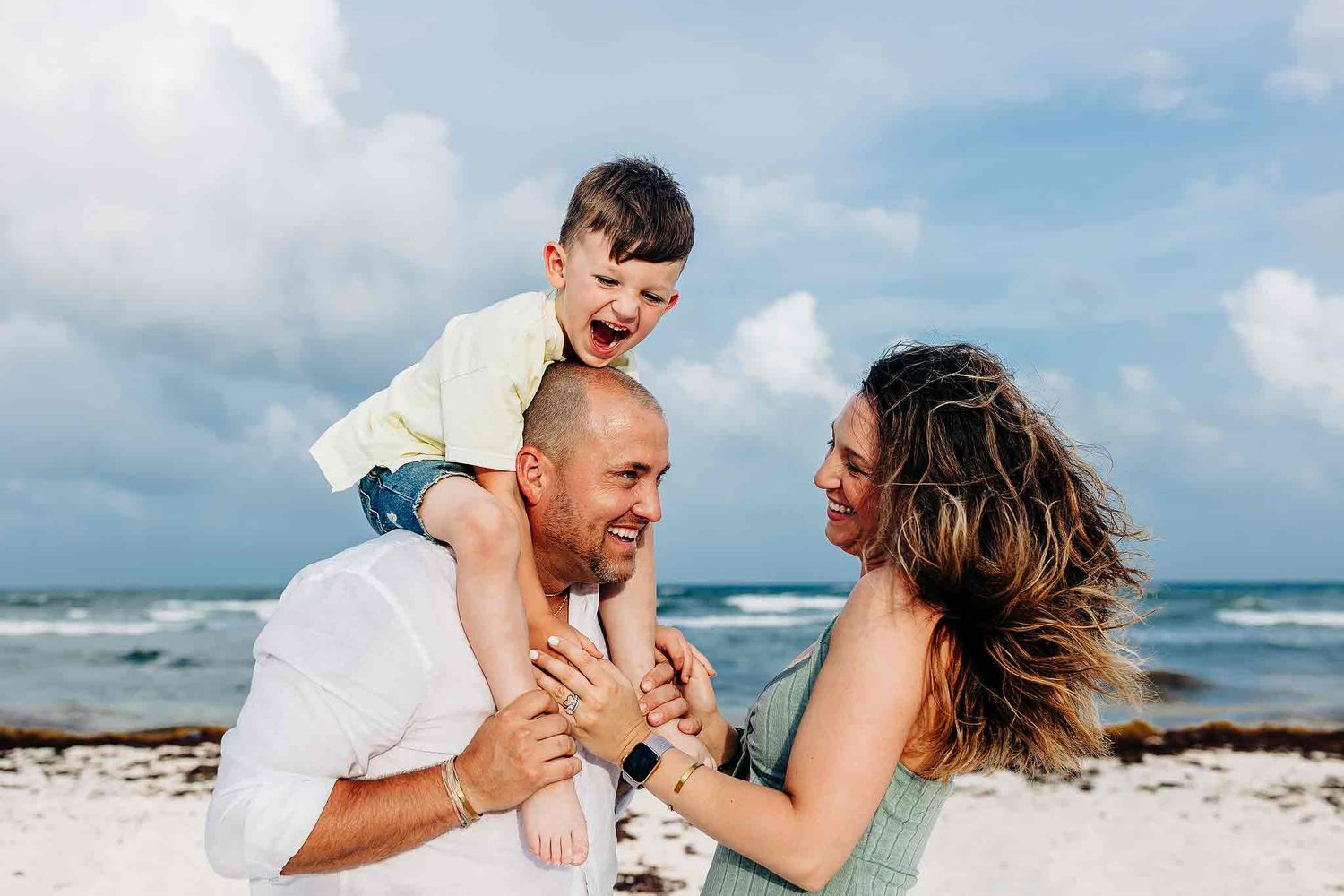 Family enjoying playful moments together by the ocean in Playa del Carmen